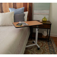 An overbed table with a tablet and a newspaper beside a made bed