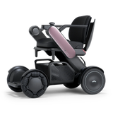 WHILL Model C2 power wheelchair with a pink arm cover, three-quarter view