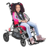 A girl seated in a red Strive adaptive stroller with the harness fastened