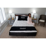 A woman sitting on the edge of a queen Flexabed Premier with the bed flat