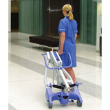 A caregiver wheeling the folded Hoyer Advance through a lobby