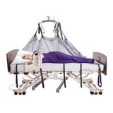 A person lying on the Hoyer Repositioning Sling, raised by a lift over a bed