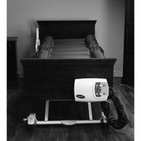A Joerns DermaFloat APL mattress on a bed, in black and white. The control unit on the foot panel is a separate part