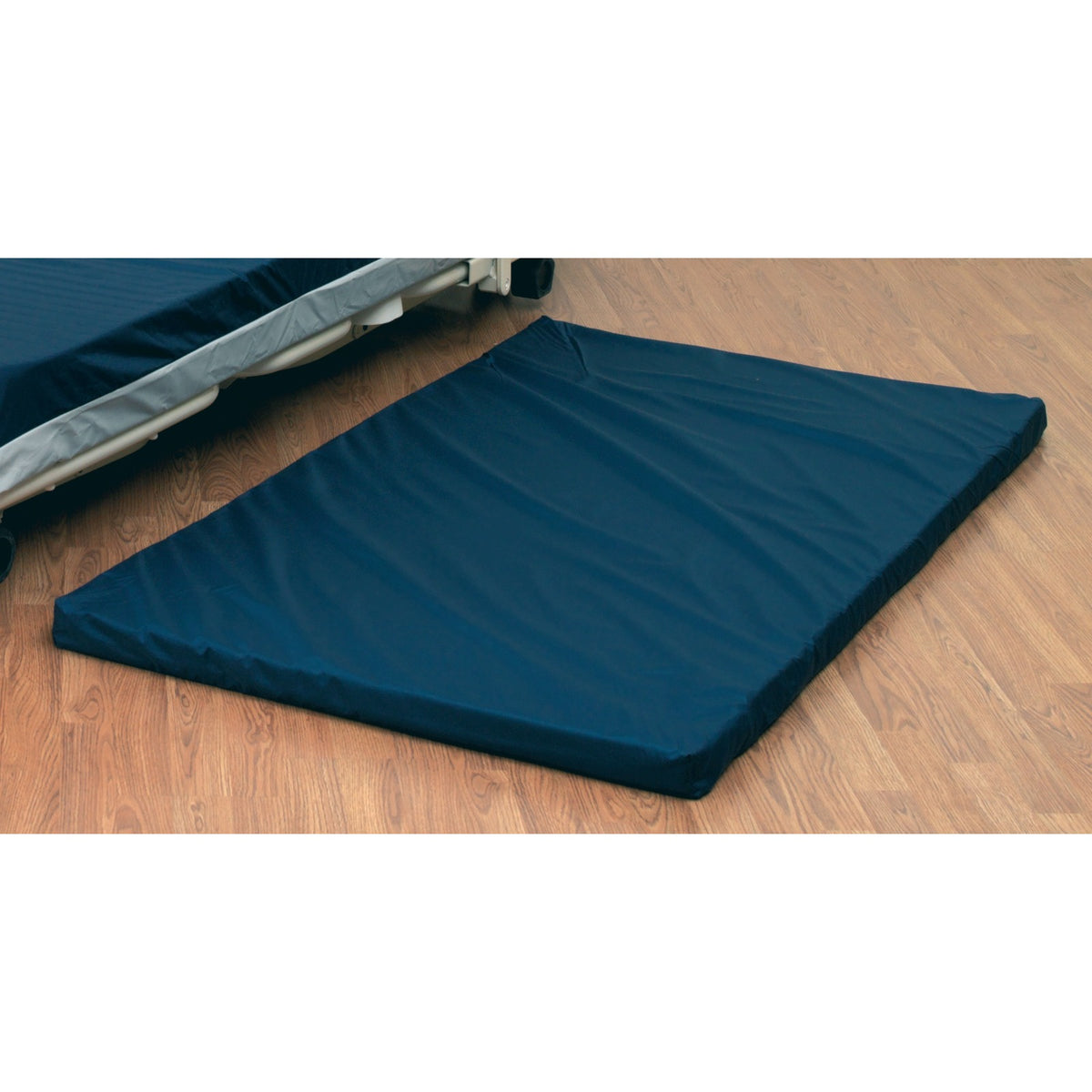 The Joerns floor mat 550132-CC, a navy pad lying on the floor beside a low bed, from the Joerns Brandfolder