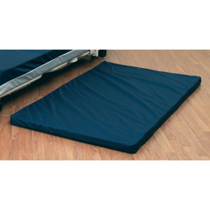 The Joerns floor mat 550132-CC, a navy pad lying on the floor beside a low bed, from the Joerns Brandfolder