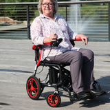 A woman driving the Journey Air Elite in Red along a waterfront path