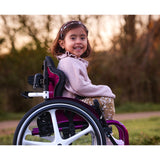 A child seated in a wheelchair with an Axiom for Kids back