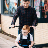 A boy walking in the MyWay+ with an adult steering by the adult guide handles add-on