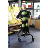 A boy standing in a Squiggles Stander with green pads and a headrest