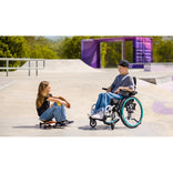 Two children at a skate park, one using the Motion Composites Helio Kids C