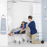A caregiver showering a child seated in the Nuprodx MC4000 Leckey