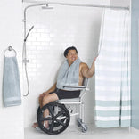 A user seated on the Nuprodx MC4020 RX in a roll-in shower