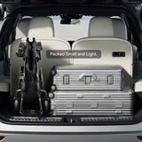 Paiseec Q5 folded and standing in an SUV cargo area beside two suitcases