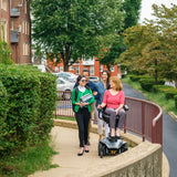 A woman riding the Pride Jazzy Air 2 power wheelchair outdoors alongside three friends