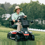 Man riding a Pride PX4 mobility scooter outdoors on grass