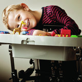 A boy smiling over the Caribou plastic tray, playing with toy blocks