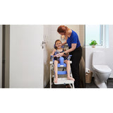 A caregiver helping a girl in a Flamingo Curo in a bathroom