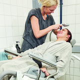 A caregiver washing a teenage girl's hair in a reclined Heron Power