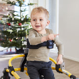 A boy pointing and smiling in a Mustang by a Christmas tree