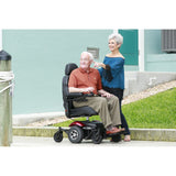 A man seated in a Merits Vision Sport power wheelchair with a woman standing beside him