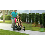 A caregiver pushing a child in a Zippie Sphynx