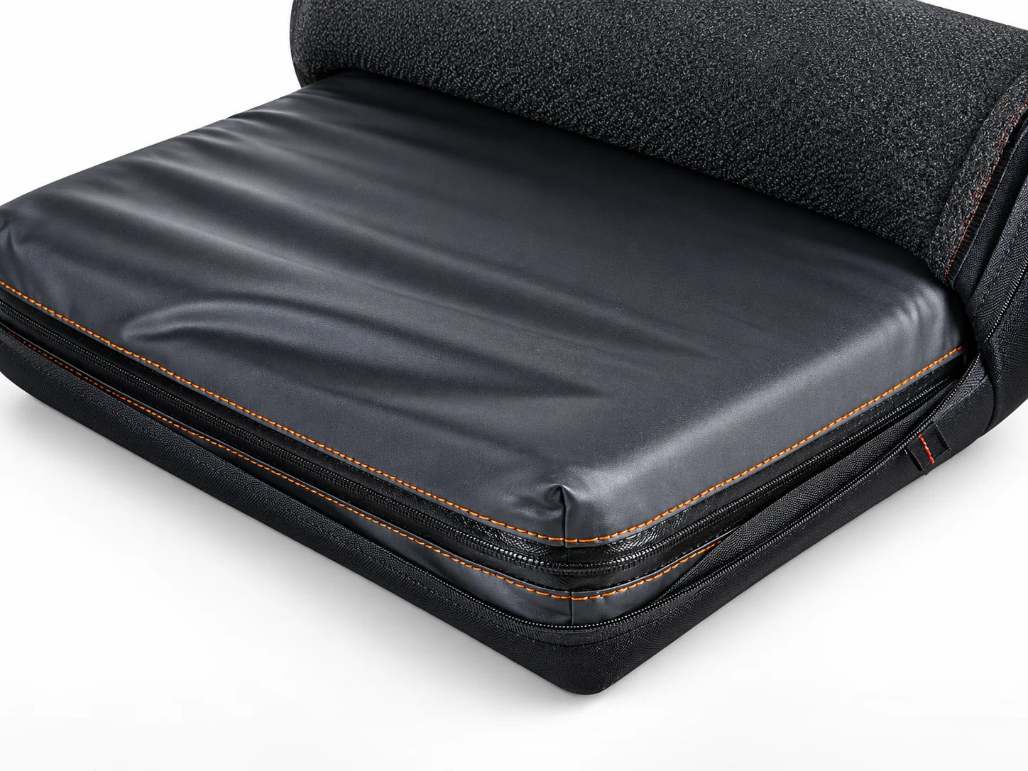 A black wheelchair cushion in its cover, with a fabric cover partly rolled back