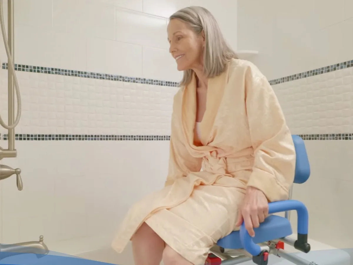 A woman in a robe sitting on a sliding swivel transfer bench beside a bathtub