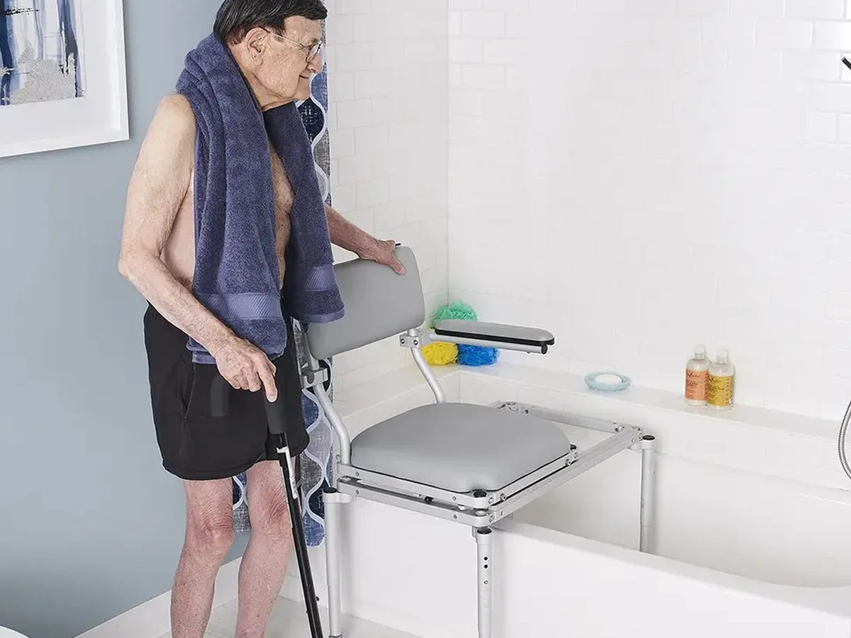 A man with a cane beside a padded tub slider seat on a bridge over the bathtub