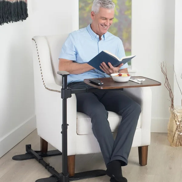 A man reading in an armchair with a swivel tray table