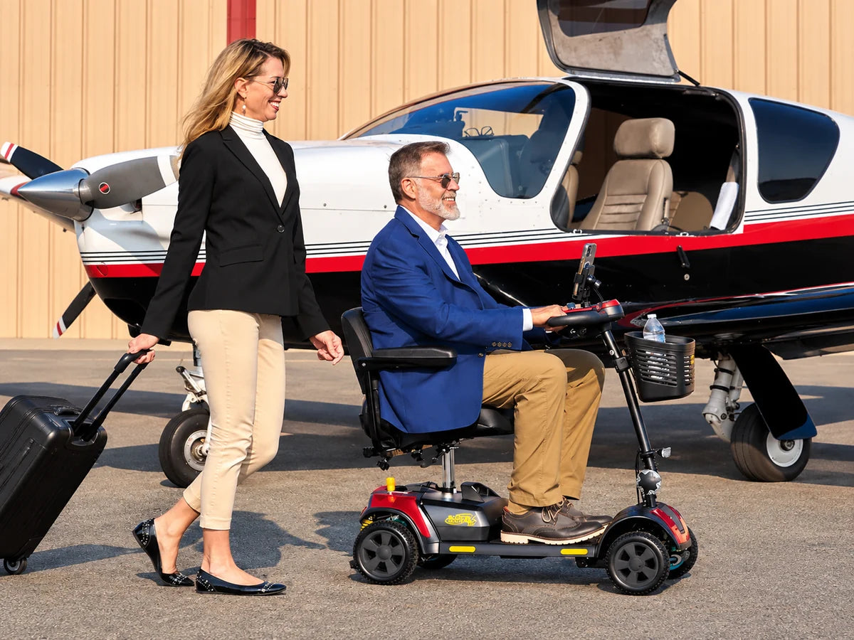 A man riding a travel mobility scooter beside a small airplane as a woman pulls a suitcase