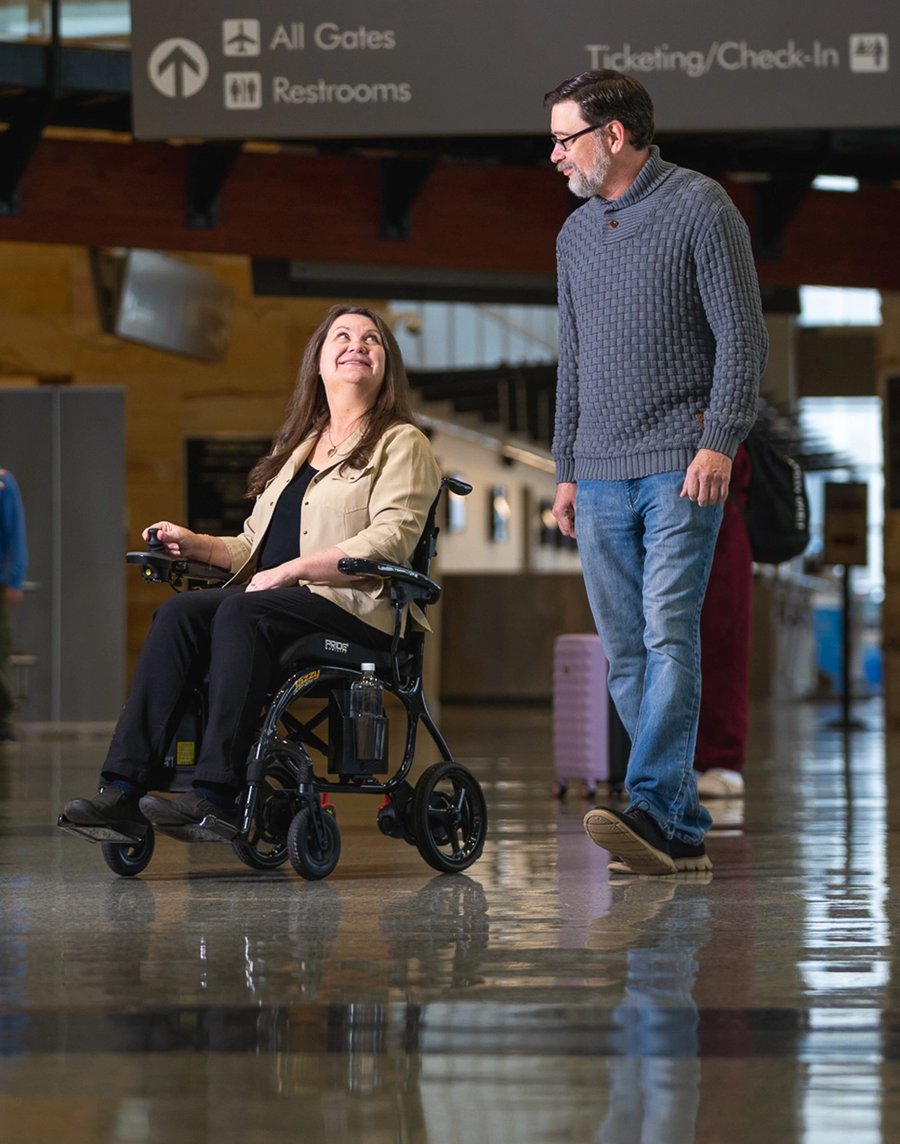 A woman using a power wheelchair with her husband