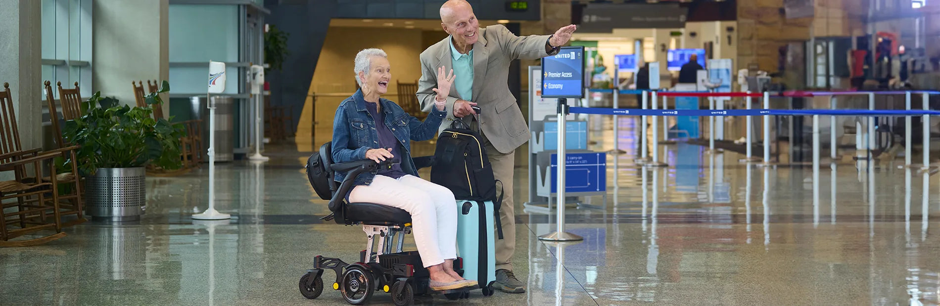 A woman in a power wheelchair and her husband at an airport check-in