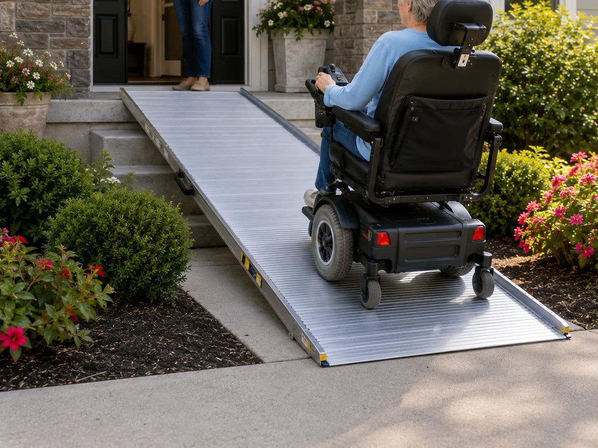A man in a power wheelchair rolling up a ramp to his front porch
