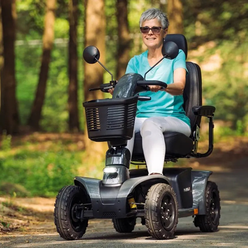 A woman riding a four-wheel mobility scooter on a wooded path