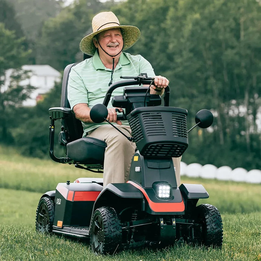 A man riding a recreational all-terrain mobility scooter on grass