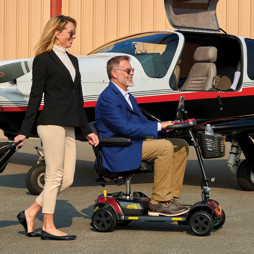A man riding a travel mobility scooter beside a small airplane
