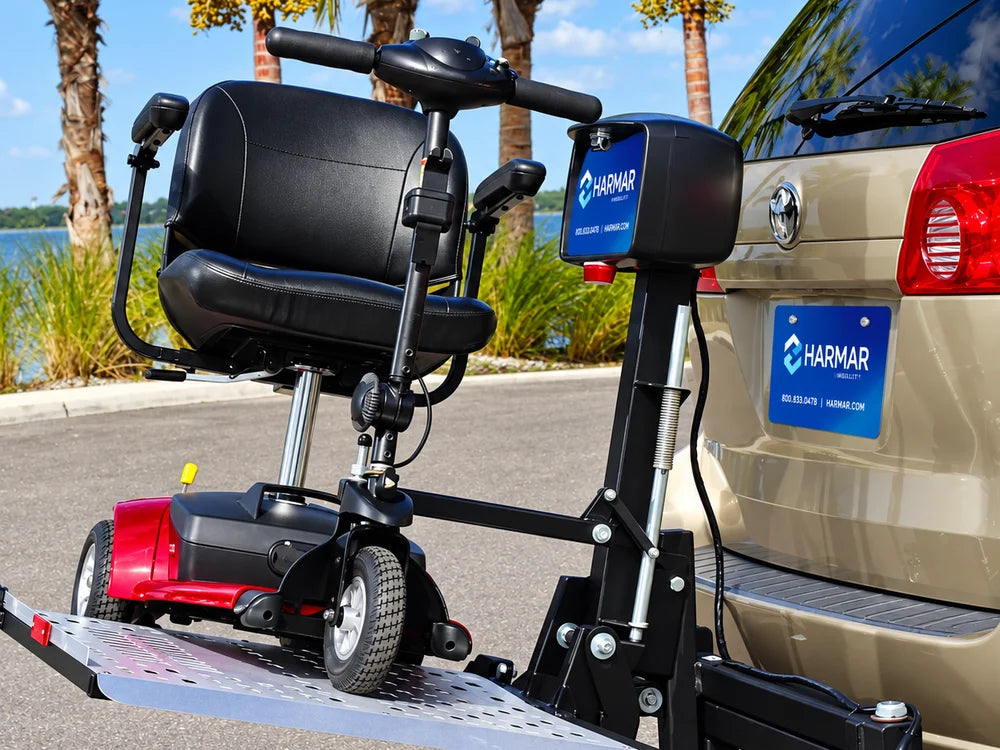 A mobility scooter on a hitch-mounted platform lift behind a minivan