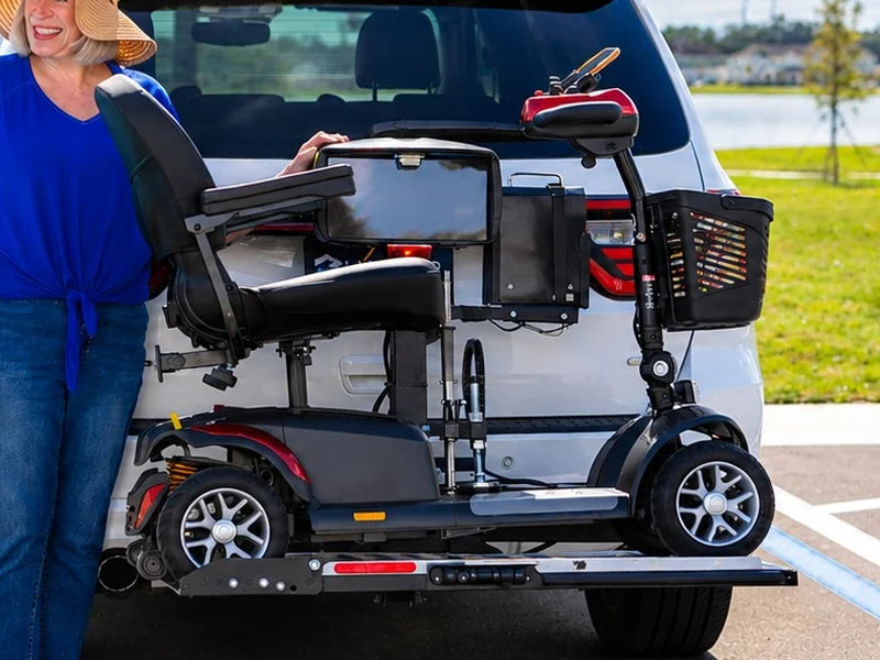 A mobility scooter carried on a platform lift at the back of a white SUV