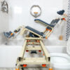 TubBuddy Tilt shower and commode chair with padded seat, adjustable footrests, corrosion-resistant aluminum frame, and tilt-in-space functionality for enhanced comfort.