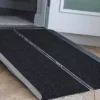 Harmar Single Fold Ramp folded in half with a carrying handle, placed on a curb, showing its lightweight and portable design.