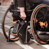Empulse R90 Power Assist Device attached to a wheelchair, providing lightweight mobility support with a range of up to 9 miles.