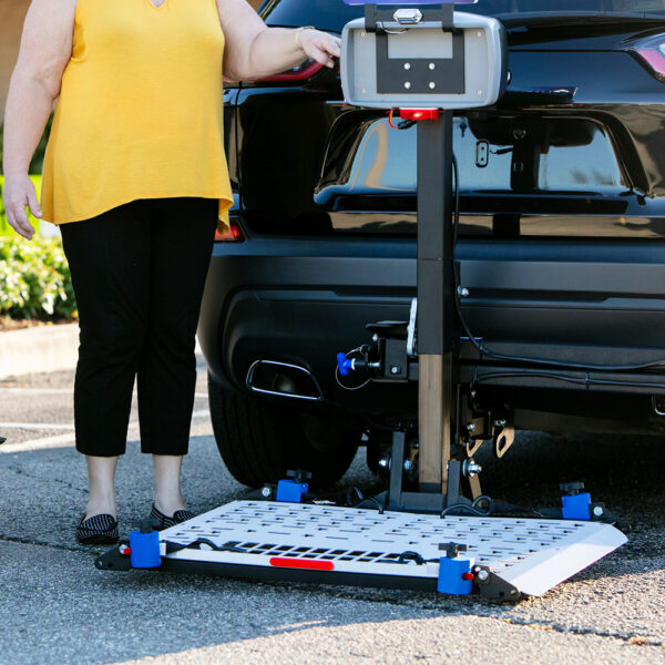 Harmar AL500HD Universal Powerchair Lift on SUV, showing adjustable platform and hold-down arm.