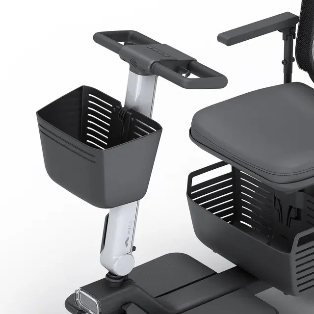 Front Basket attached to WHILL Model Ri tiller, spacious and detachable for carrying groceries and personal items.