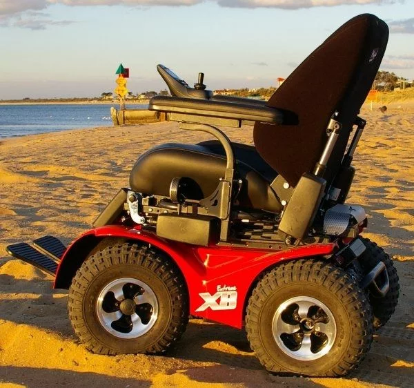 Extreme X8 Power Wheelchair navigating rugged outdoor terrain with knobby tires and a sturdy design, built for sand, snow, and off-road adventures.