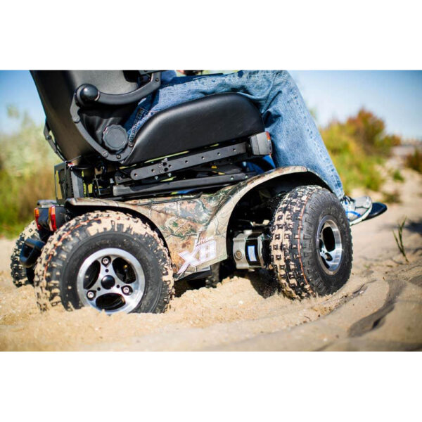 Extreme X8 Power Wheelchair navigating rugged outdoor terrain with knobby tires and a sturdy design, built for sand, snow, and off-road adventures.