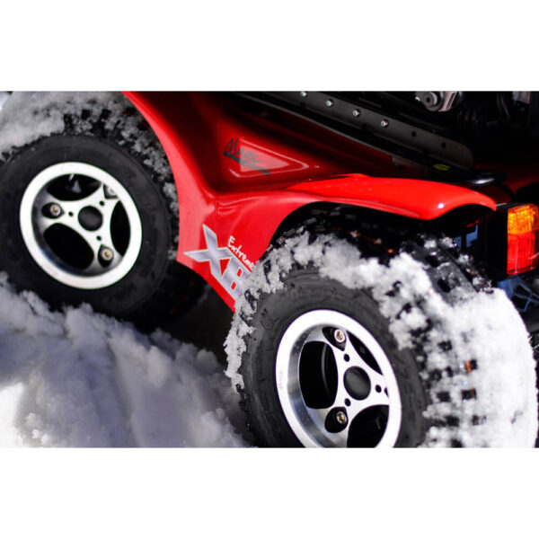 Extreme X8 Power Wheelchair navigating rugged outdoor terrain with knobby tires and a sturdy design, built for sand, snow, and off-road adventures.