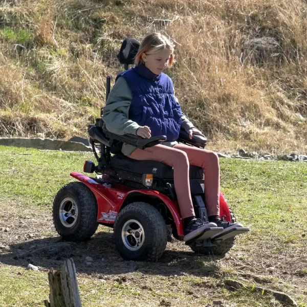 Extreme X8 Power Wheelchair navigating rugged outdoor terrain with knobby tires and a sturdy design, built for sand, snow, and off-road adventures.