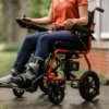 GoRide 2 Electric Wheelchair in orange, foldable aluminum frame, padded seat, 12” rear wheels, and ergonomic joystick controls.